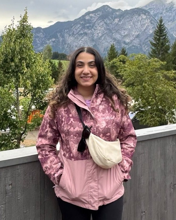 Nour Essam smiling on a balcony with mountains behind her